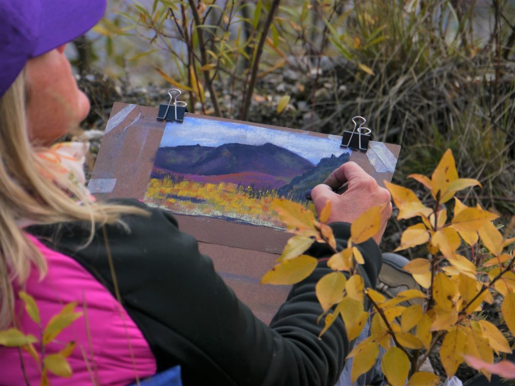 An image of Renata Bradshaw painting a landscape art piece.